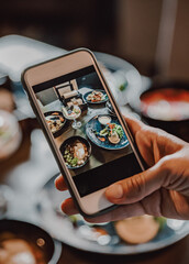 woman hand with smartphone photographing food at restaurant or cafe