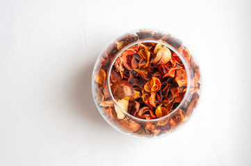 Vase made of transparent glass with dried flower petals on white background