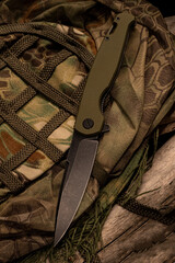 A knife lying on a military uniform. Knife and camouflage clothing. Disguise.