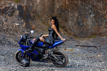 Fototapeta na wymiar Attractive girl on a motorbike posing outside in leather dress