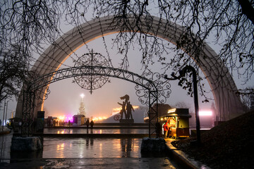 Evening view of the People's Friendship Arch in the park in foggy weather. Kyiv, Ukraine. December 2020
