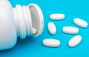 Plastic medical container with scattered white pills on blue.