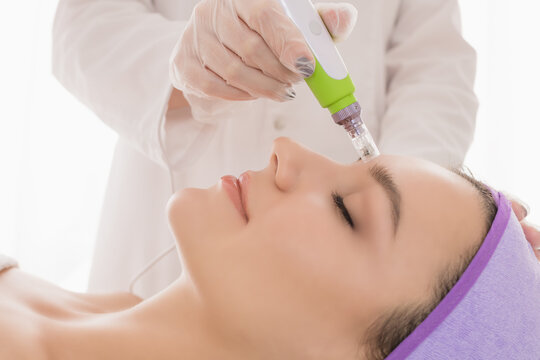 Fractional mesotherapy.A young beautiful woman in the cosmetologist&rsquo;s office receives fractional mesotherapy for her face. Facial skin rejuvenation. Acne treatment. Hardware cosmetology. Beautician.