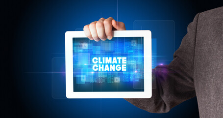 Young business person working on tablet and shows the inscription: CLIMATE CHANGE