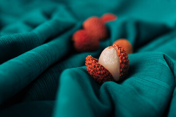 Closeup aesthetic of fresh organic Lychee (Litchi fruit) against  dark cyan cloth background. Concept healthy food, diet, vegan