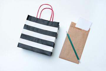 Striped paper bag, letter and green pencil, white background, copy space