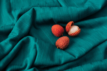 Flat lay of of  fresh organic Lychee (Litchi fruit) against  dark cyan cloth background.