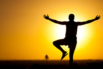 Fototapeta premium silhouette of a man on the mountain watching the sunset with open arms