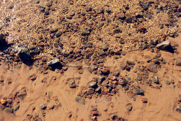 Transparent sea water and bottom with rocks, close-up, top view