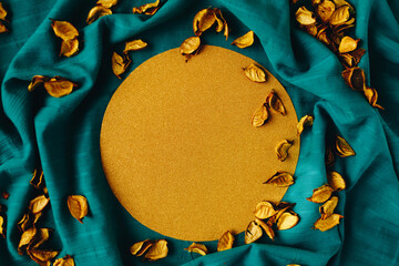 Sunny gold shape rounded with yellow dry leaves on the dark cyan background. Autumn, end of life circle concept.