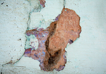 Parte de una pared con capas de pintura azul, blanca y marrón dañada por el paso del tiempo en la...