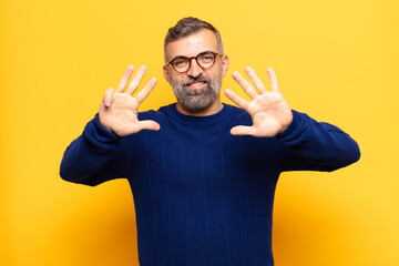 adult handsome man smiling and looking friendly, showing number nine or ninth with hand forward,...