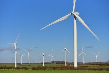 A large windmill against a blue sky, with other windmills in the background.