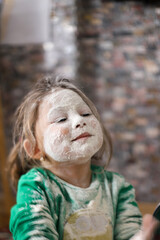 Funny little girl having fun in the kitchen to prepare cookies.