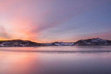 Natural sunset background. An ice-covered mountain lake. Magic Magenta sunset on a mountain North of the lake.