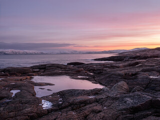 Wonderful mountain landscape with a Cape on the shore of the Barents sea. Amazing sunrise landscape with polar white snowy range of mountains.