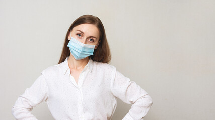 Unhappy woman in a medical mask, grimace of sadness, white background, 16: 9, copy space