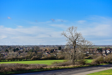 Landscape with a green field and blue sky, with a small town in the background.