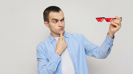 Pensive funny man kinofan removes pixel glasses, portrait, white background, copy space, 16: 9
