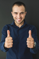 Businessman enjoys successful contract and shows super sign with fingers, black background, vertical