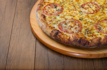 Close-up photograph of Mozzarella Cheese Pizza with sliced ​​red tomatoes on a wooden board. Space for texts on the left.