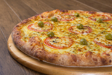 ricardo fernando franca junior pizza mussarela muçarela mucarelTasty mozzarella cheese pizza with slices of red tomatoes on a wooden board. Horizontal gastronomic photograph with blurred background.