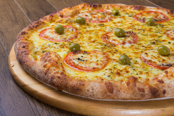 Mozzarella cheese pizza with slices of red tomatoes on a wooden board. Gastronomic photography.