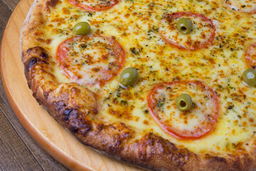 Gourmet close-up photo of a Mozzarella Cheese Pizza with sliced ​​red tomatoes on a wooden board.
