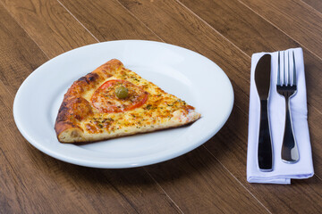 ricardo fernando franca junior pizza mussarela muçarela mucarelTasty slice of mozzarella cheese pizza with slices of red tomatoes. Fork and knife on the right ready to be used in the meal.