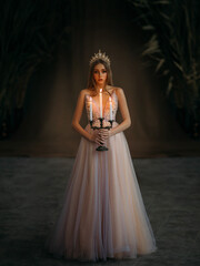 Art photo of medieval girl princess walks in dark gothic room. Woman queen holding candlestick with...