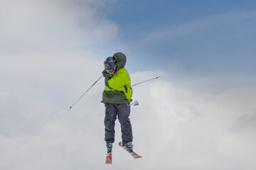 Professional skier jumping through the air and doing impressive skills against the cloudy sky