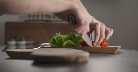 Man slicing cherry tomatoes for sandwich on kitchen countertop