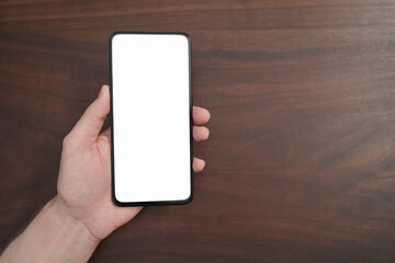 Man hand hold phone with white screen over black walnut table background