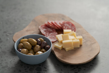 olives, salami and vintage cheese on concrete countertop