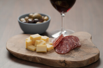 olives, salami and vintage cheese with glass of red wine on walnut table