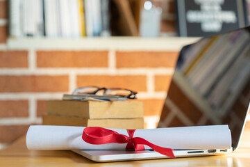 close up  bachelor's degree certificate on laptop with book in the library for online learning...