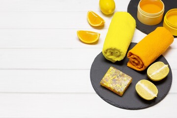 Natural organic skin care cosmetics concept. Homemade citrus soap with lemons, oranges and towels on white wooden board table. Copy space