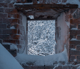 View through an empty window of old ruined brick building.