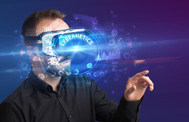 Businessman looking through Virtual Reality glasses with CYBERNETICS inscription, innovative technology concept