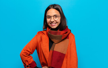 hispanic woman smiling happily with a hand on hip and confident, positive, proud and friendly...