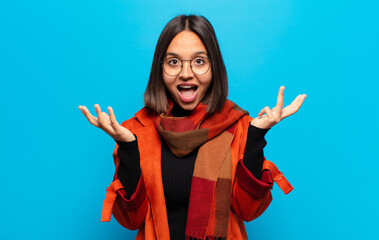 hispanic woman feeling happy, excited, surprised or shocked, smiling and astonished at something...