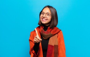 hispanic woman smiling proudly and confidently making number one pose triumphantly, feeling like a...