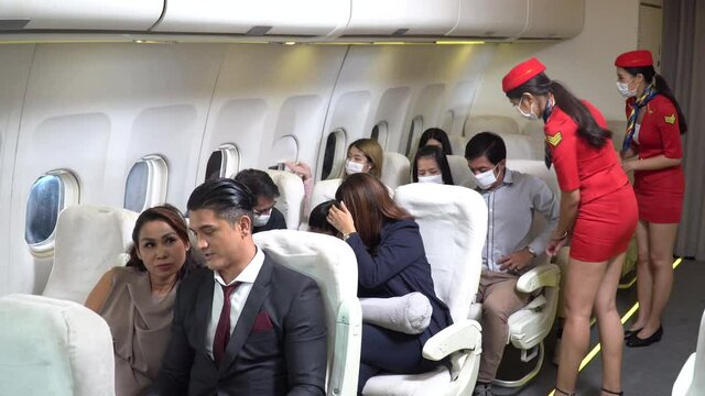 couple business passengers forget  do not wearing protective face mask sitting in airplane. Stewardess walking to checking and Remind travel tourist wear mask during  coronavirus or Covid-19 pandemic