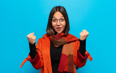 hispanic woman celebrating an unbelievable success like a winner, looking excited and happy saying...