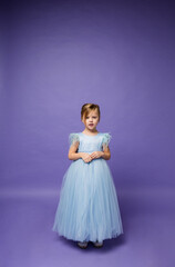 a little girl in a puffy blue princess dress stands on a purple background with space for text