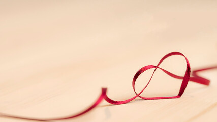 heart ribbon in red color background for valentines day with copy space, love ribbon isolated as a bottom border, valentines day ribbon decoration on light background, silk texture