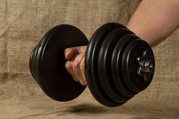 Heavy collapsible dumbbell in the hand of an athlete. Sports equipment with rubberized discs.