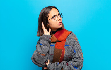 hispanic woman looking serious and curious, listening, trying to hear a secret conversation or...