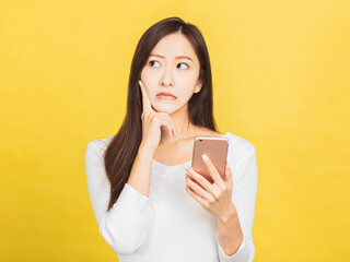  young woman holding smartphone and thinking about