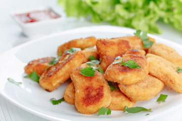 Fried chicken nuggets with ketchup sprinkled with chopped parsley.